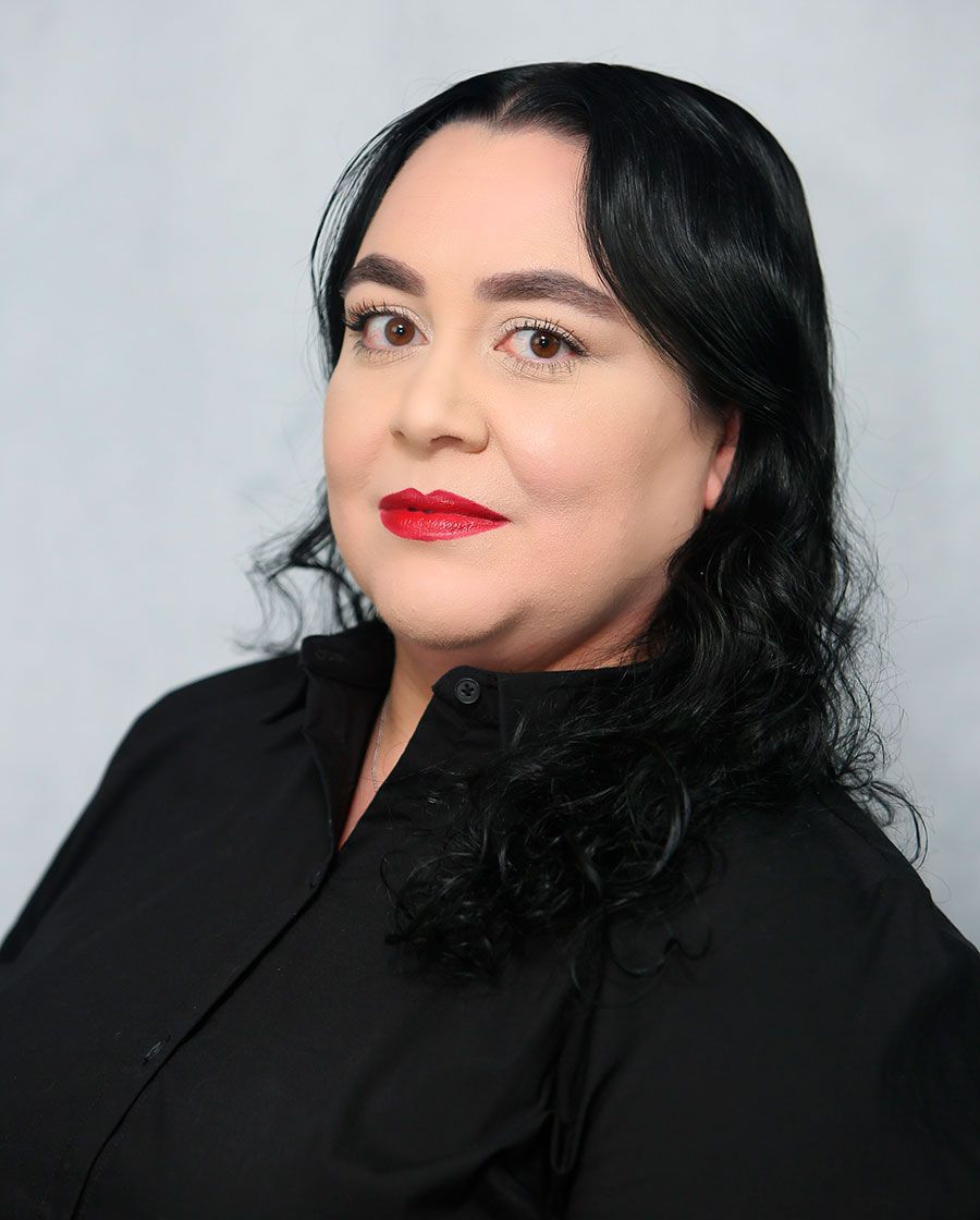 portrait of larissa. she has wavy black hair and is wearing a black blouse and bright red lipstick
